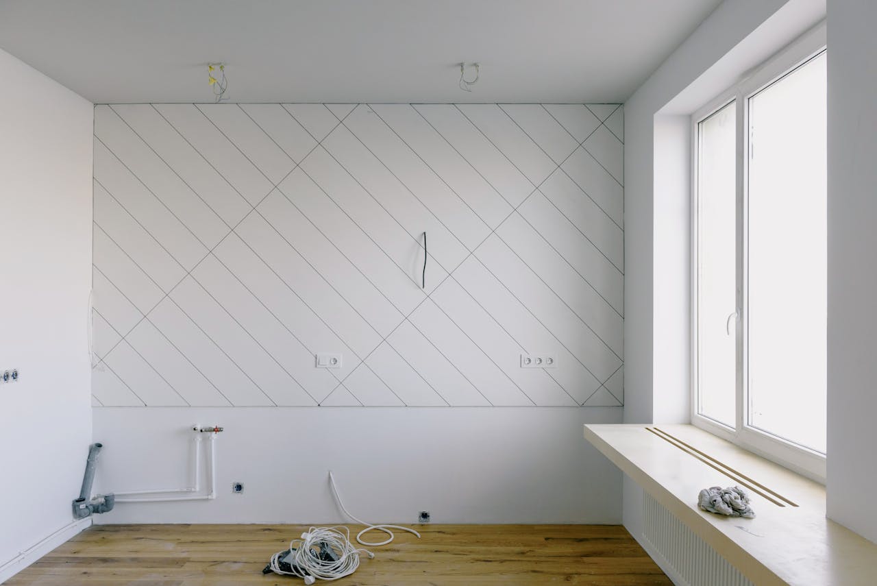 Chambre moderne avec des matériaux de rénovation, notamment des câbles et un plancher en bois, la lumière du jour pénétrant par la fenêtre.